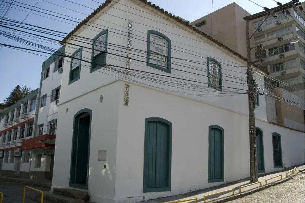 Fachada do Museu Victor Meirelles, prédio histórico branco com janelas e portas verdes, localizado no centro de Florianópolis.