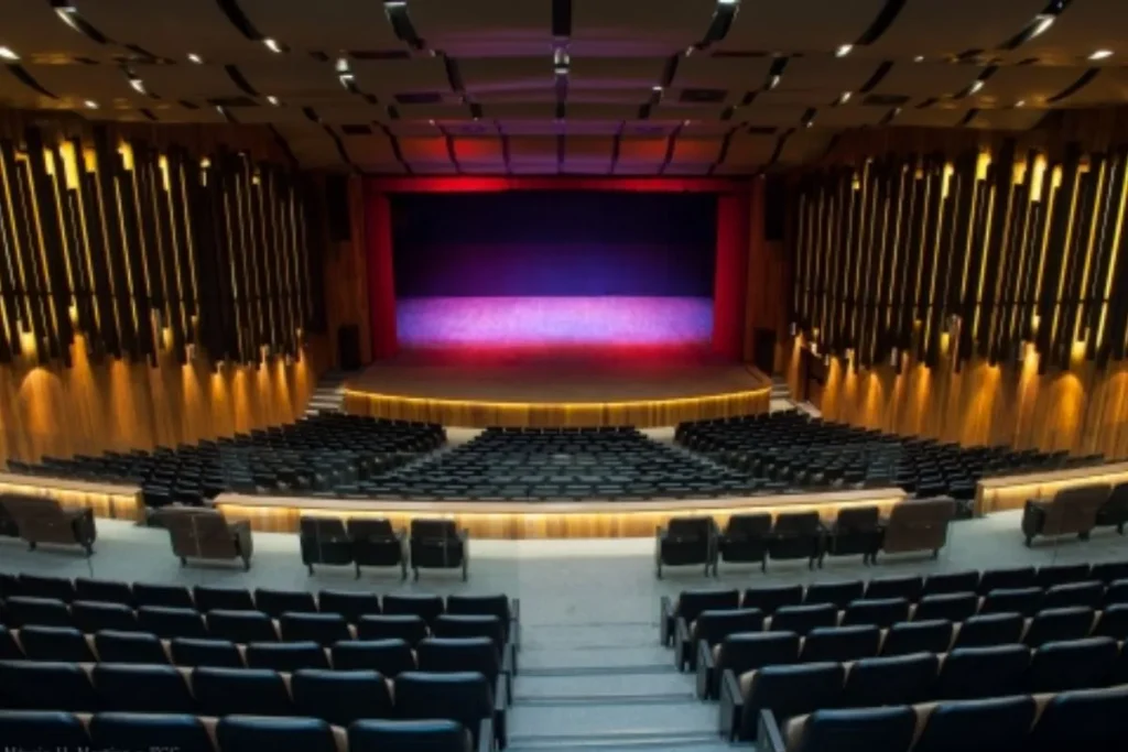 Vista interna do Teatro Ademir Rosa (CIC) em Florianópolis, com amplo palco iluminado e poltronas dispostas em semi-arena.