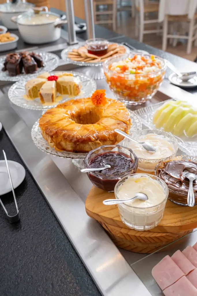 Buffet café da manhã Bossa Jurerê com bolos, frutas e doces